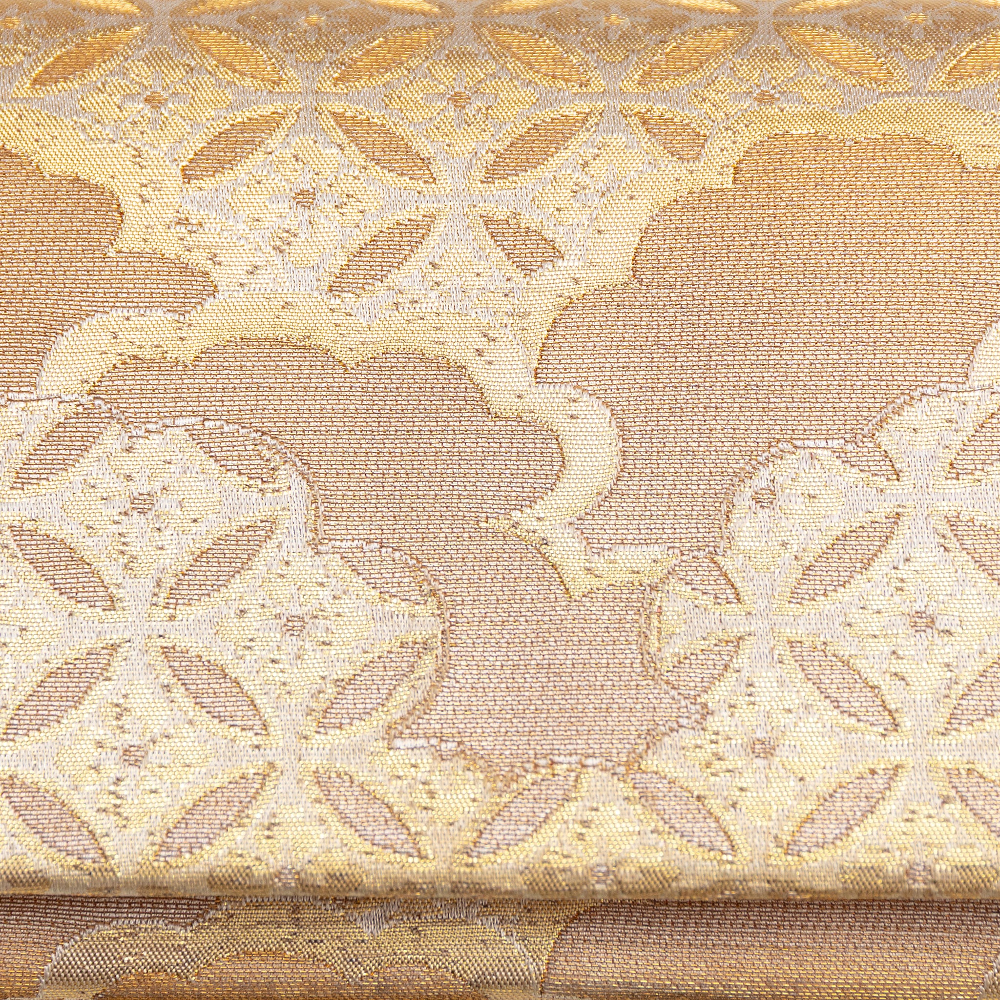 Close-up of the gold silk envelope clutch’s intricate shippo cloud embroidery and shimmering texture from a side angle