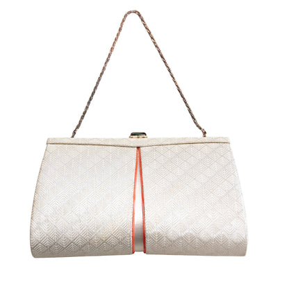 White textured handbag with a silver fancy chain strap and orange accents on a white background