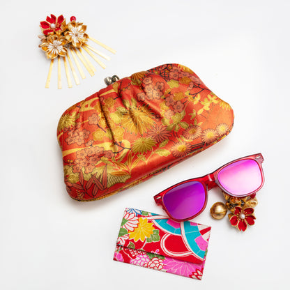 Colourful vintage Japanese leather clutch bag, sunglasses, and hairpin on a white background