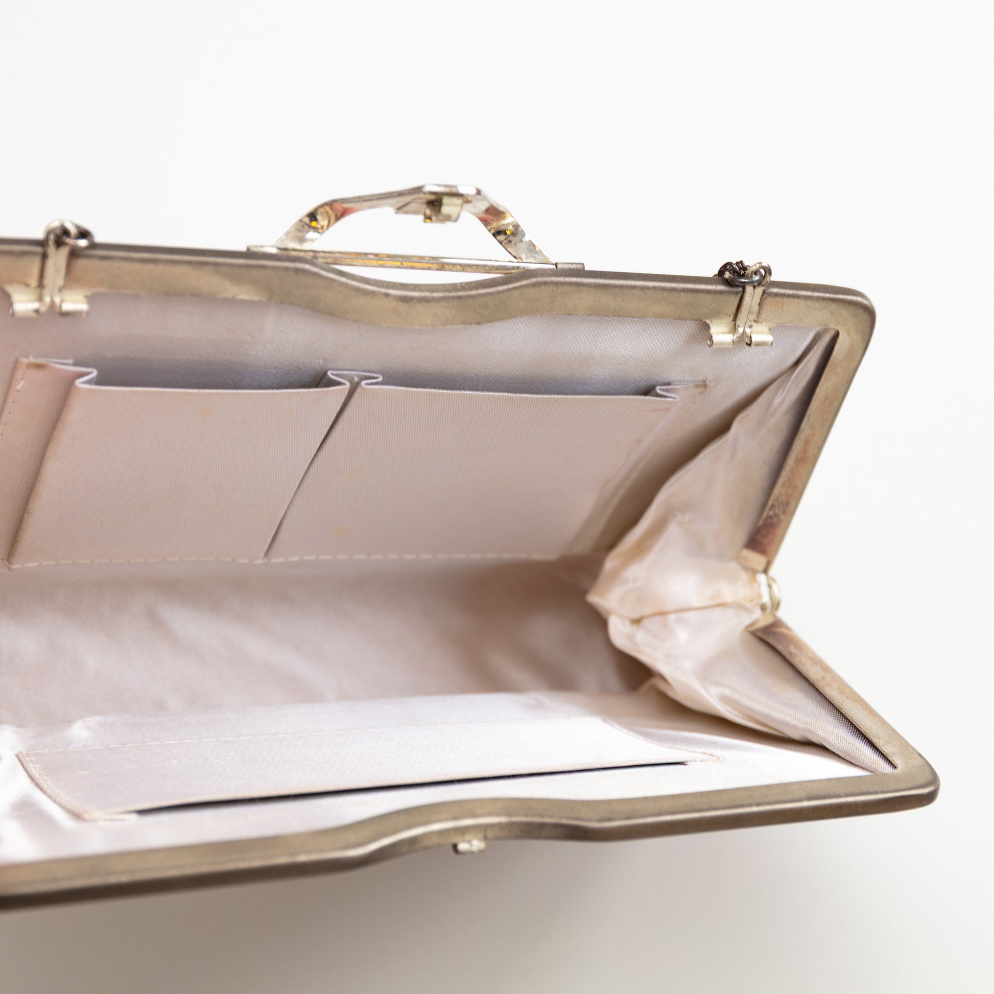 Pink ombre handbag with open compartment lined in white silk with internal pockets on a light gray background