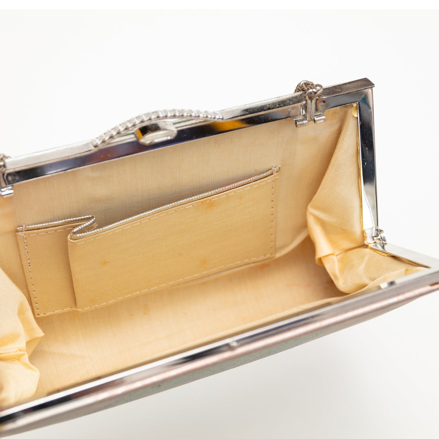 Gold beige silk lined clutch bag with a silver frame on a white background