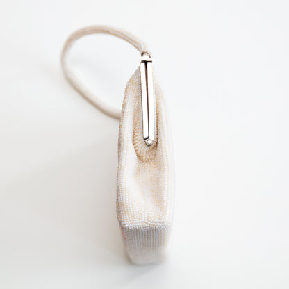 Side view of 1960s vintage white beaded  evening bag with silver metal frame and beaded strap on white background.