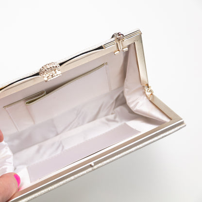 Close-up of a silver and white clutch with a decorative clasp on a white background. The hinges old in or out depending on if you want to use the chain strap or not.