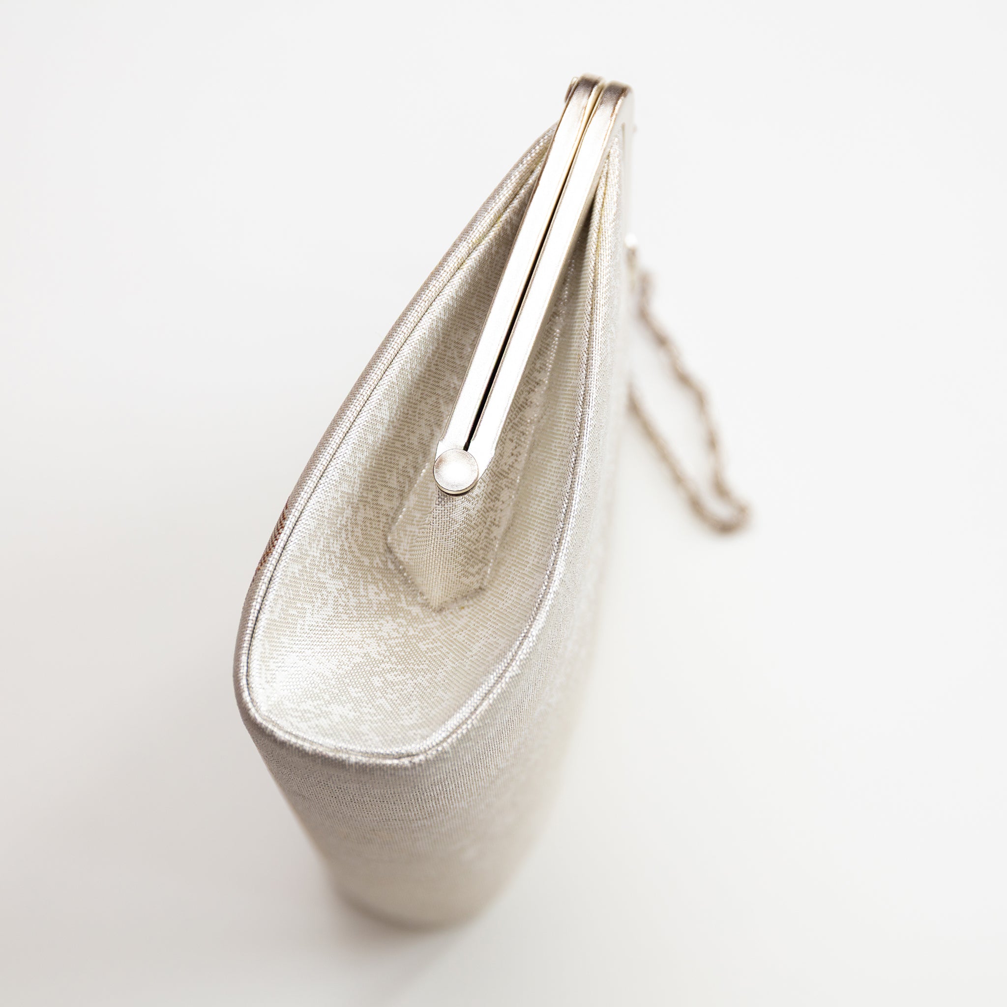 Close-up of intricate embroidered floral details and shimmering silk texture on the front of the ivory vintage kimono clutch