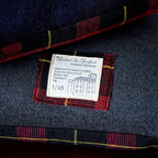 Close-up of grey tartan wool fabric texture highlighting the intricate weave and subtle color variations on the Cushion
