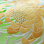 Close-up of green silk floral pattern highlighting intricate Kiku embroidery and texture at a diagonal angle.