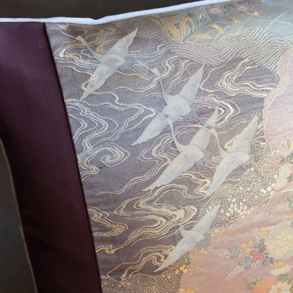 Close-up of purple flying cranes embroidery highlighting intricate rose gold silk thread detailing and textured stitching.