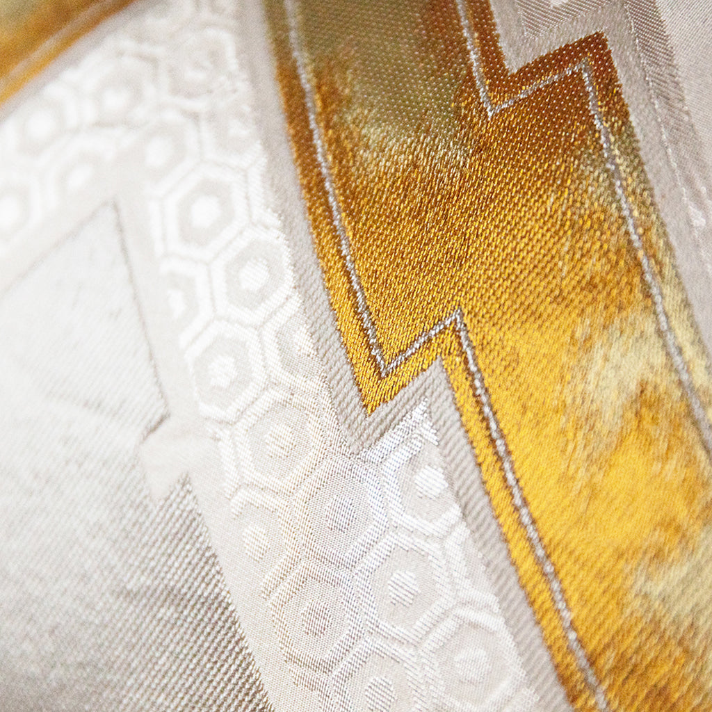 Close-up of gold and silver accents on the textured fabric, highlighting intricate embroidery and shimmering thread details.