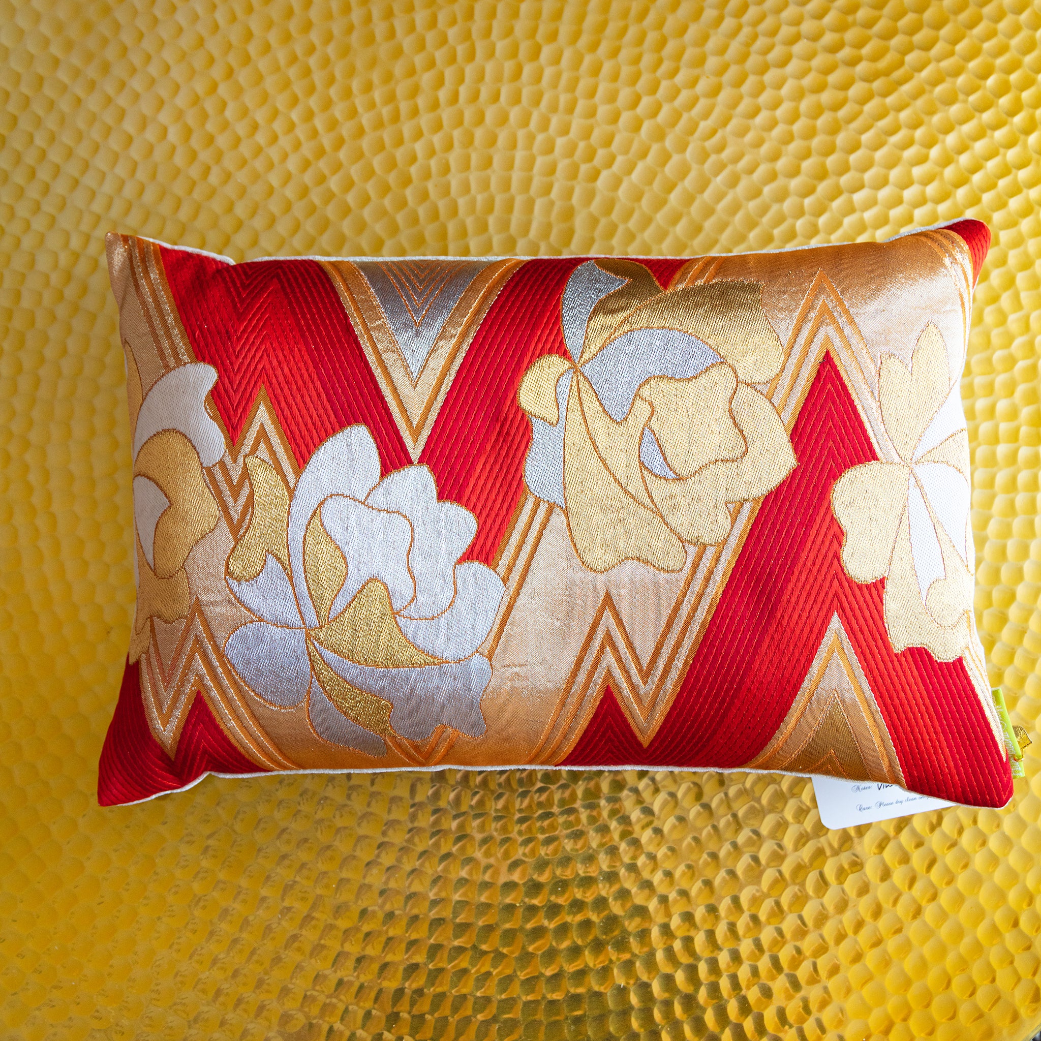 Close-up of red zigzag woven fabric and gold floral embroidery highlighting intricate texture detail of the vintage kimono