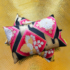 Close-up of pink silk pillow with gold accents showing textured embroidery and intricate stitching detail