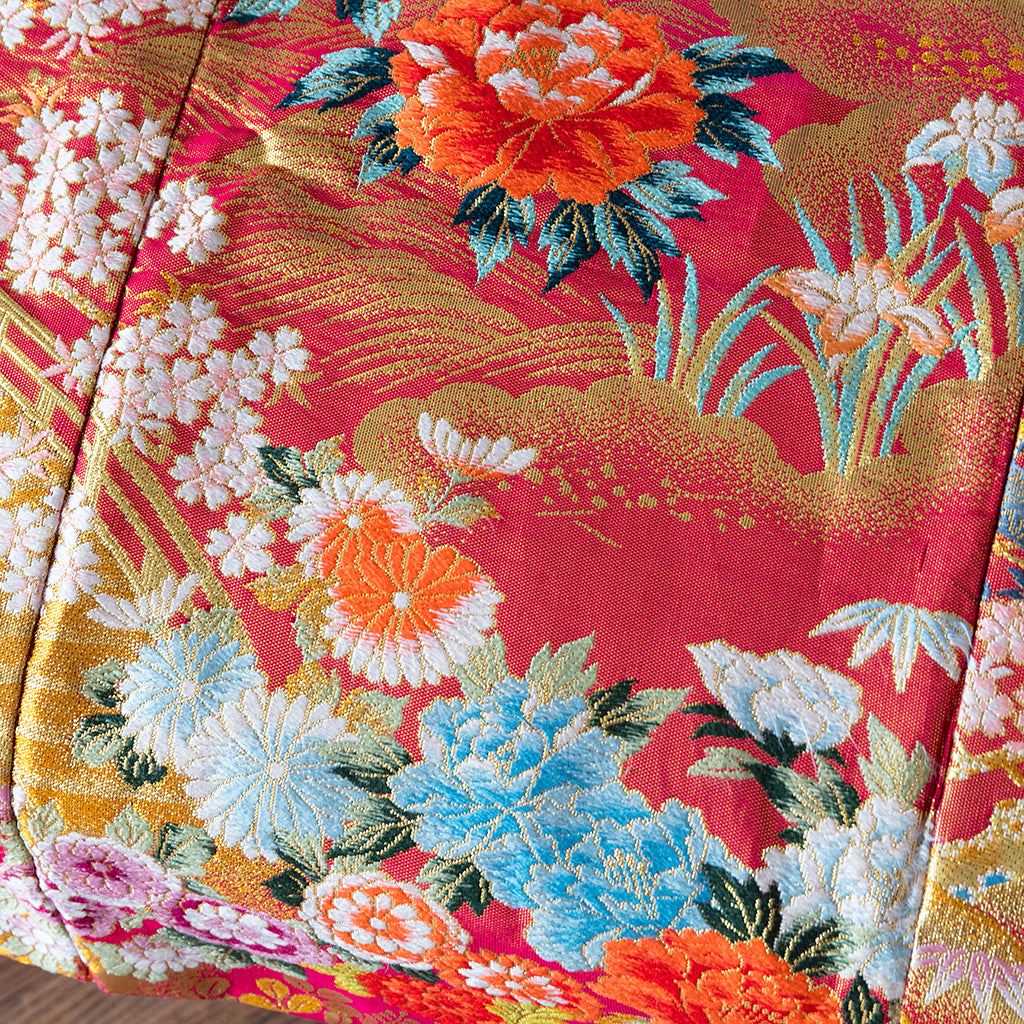Close-up of the intricate silk embroidery detail on the kimono's sleeve border, highlighting hand-stitched floral motifs and