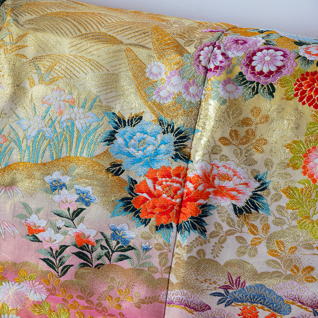 Close-up of intricate silk kimono fabric showcasing vibrant, detailed floral embroidery with subtle shimmering threads