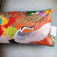 Detail of orange asian birds cushion showing a crane and wing over flowers and leaves by Hunted and Stuffed