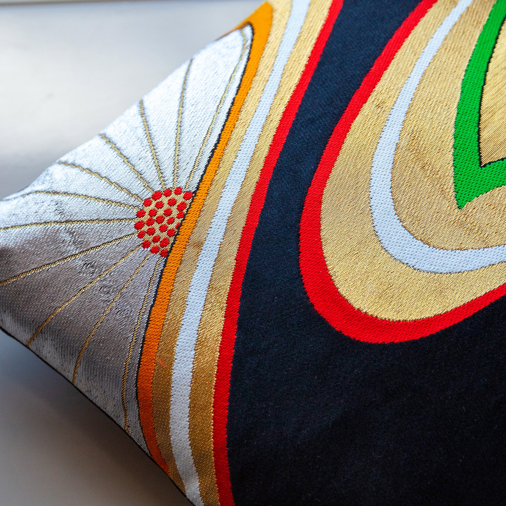 Close-up of the gold floral embroidery detail on black silk pillow surface, highlighting intricate threadwork and luxurious