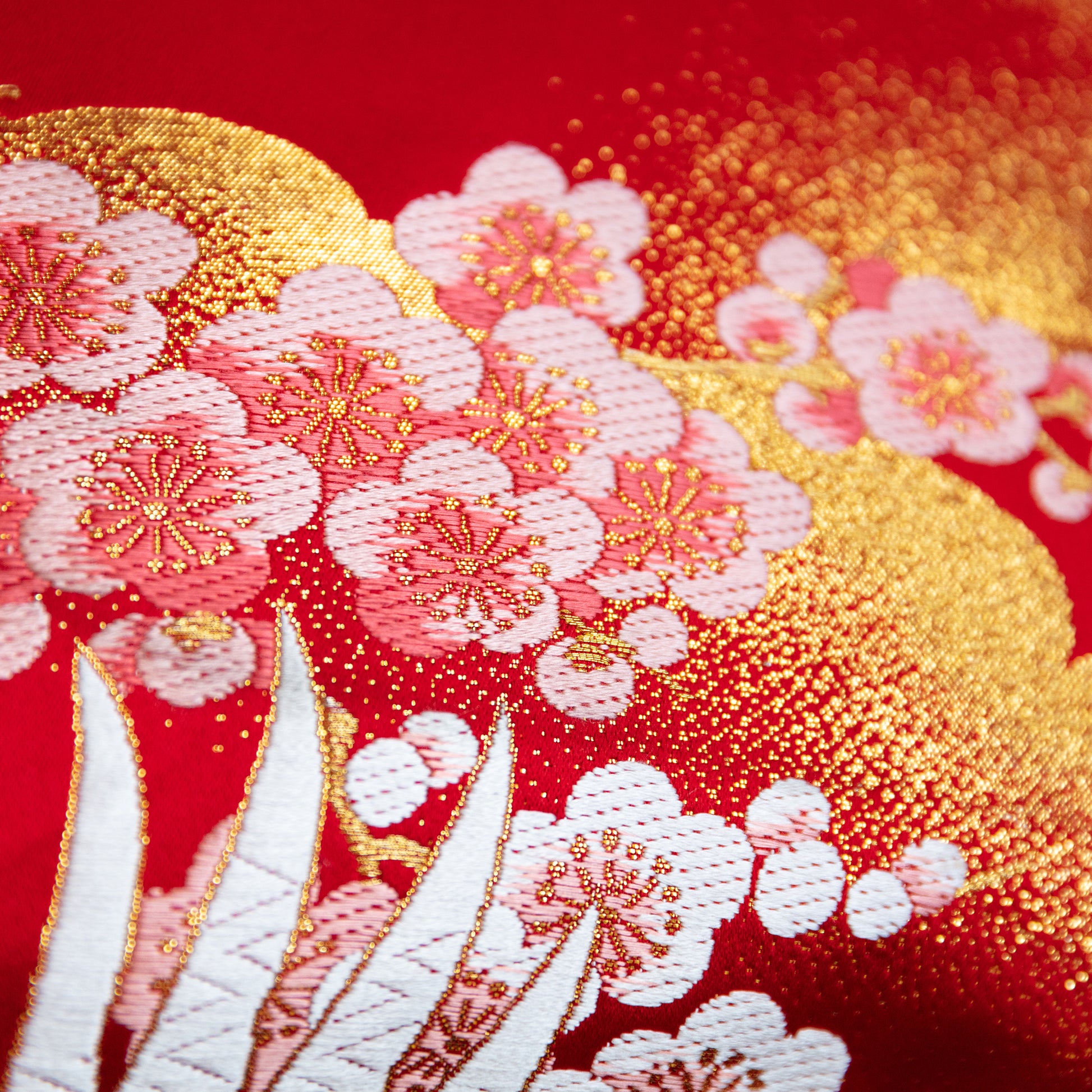 Close up of woven blossom in pink with gold acccents over a red silk base. A vintage obi repurposed as a pillow.
