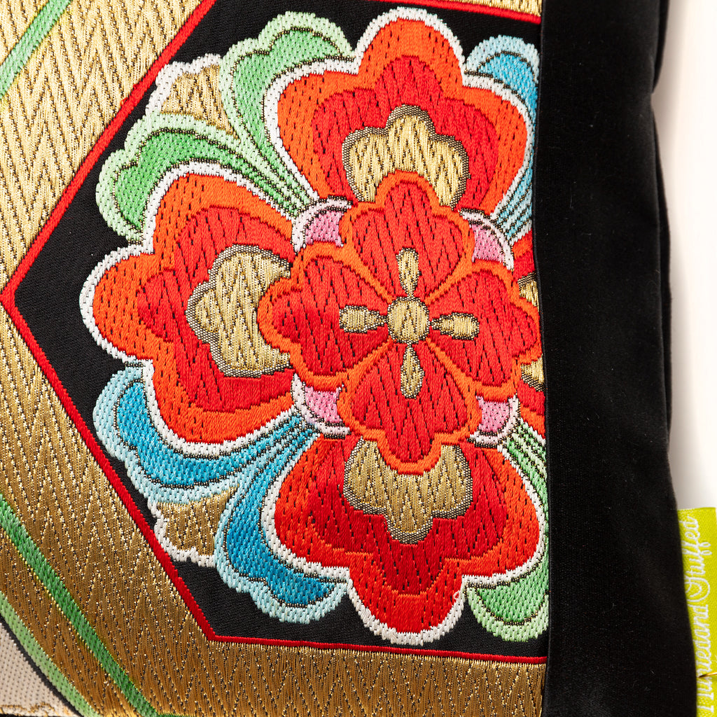 Close-up of gold hexagon embroidery on black silk fabric, highlighting intricate stitch detail and textured surface.