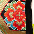 Close-up of gold hexagon embroidery on black silk fabric, highlighting intricate stitch detail and textured surface.