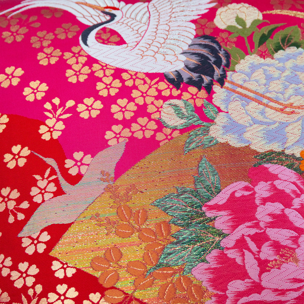 Close-up of pink silk and velvet textures highlighting intricate crane embroidery and vintage Uchikake style on the pillow