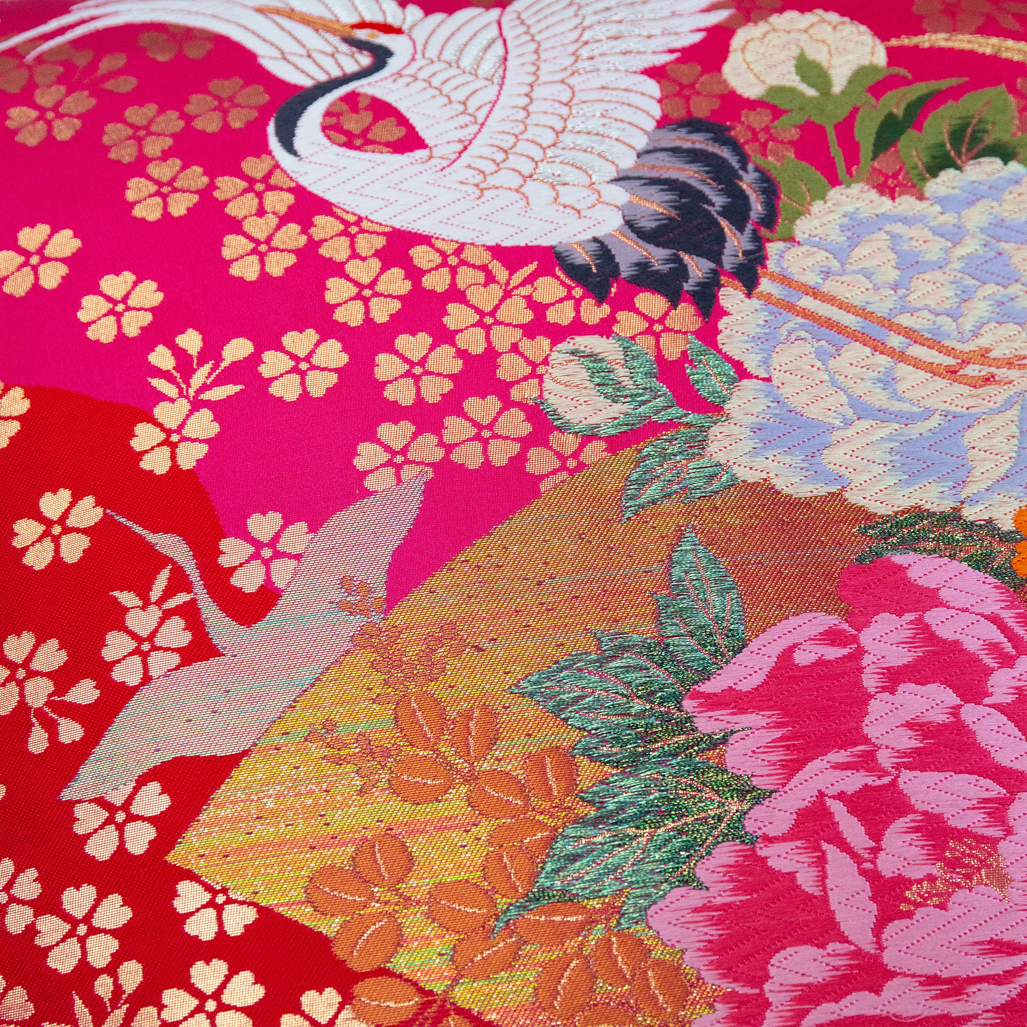 Close-up of pink silk and velvet textures highlighting intricate crane embroidery and vintage Uchikake style on the pillow