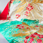 Close-up of gold phoenix embroidery on silk throw blanket edge, showcasing intricate vintage detailing and vibrant gold