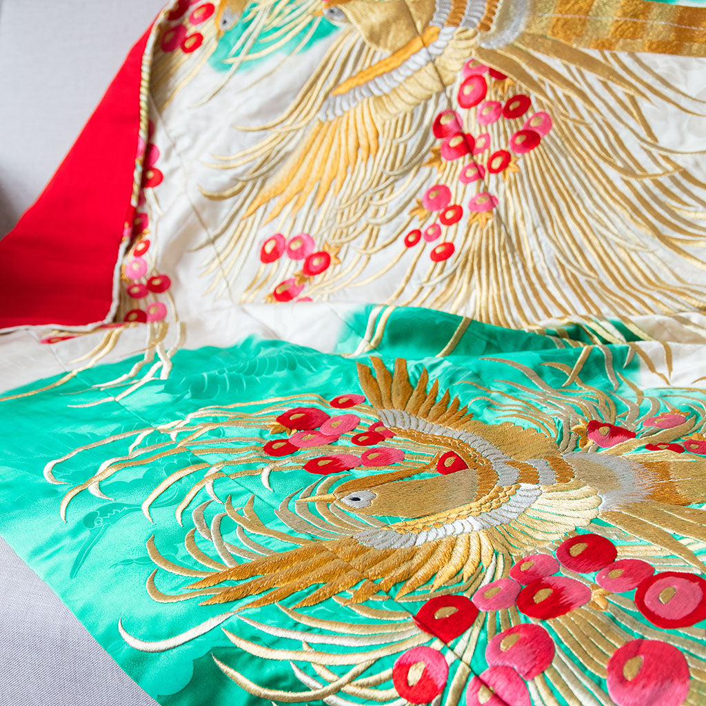 Close-up of gold phoenix embroidery on silk throw blanket edge, showcasing intricate vintage detailing and vibrant gold