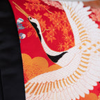 Close-up of red silk embroidered flying cranes detail on black velvet cushion showing intricate stitching and textured