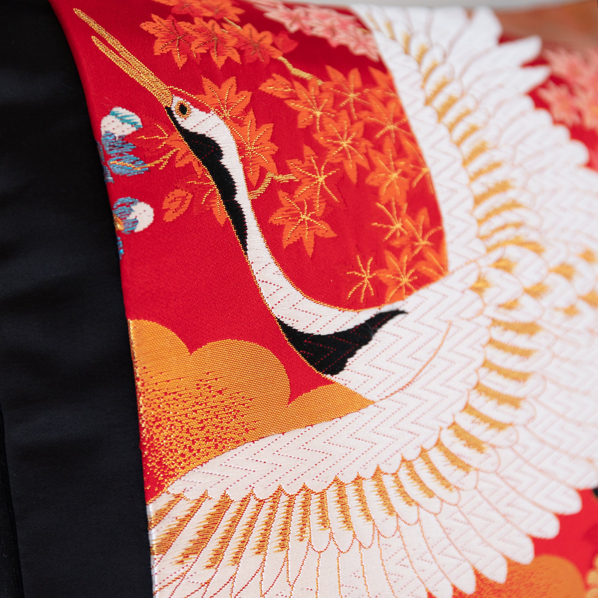 Flying crane woven in white silk thread over a red silk base with metallic gold accents. Detail of a throw pillow by Hunted and Stuffed.