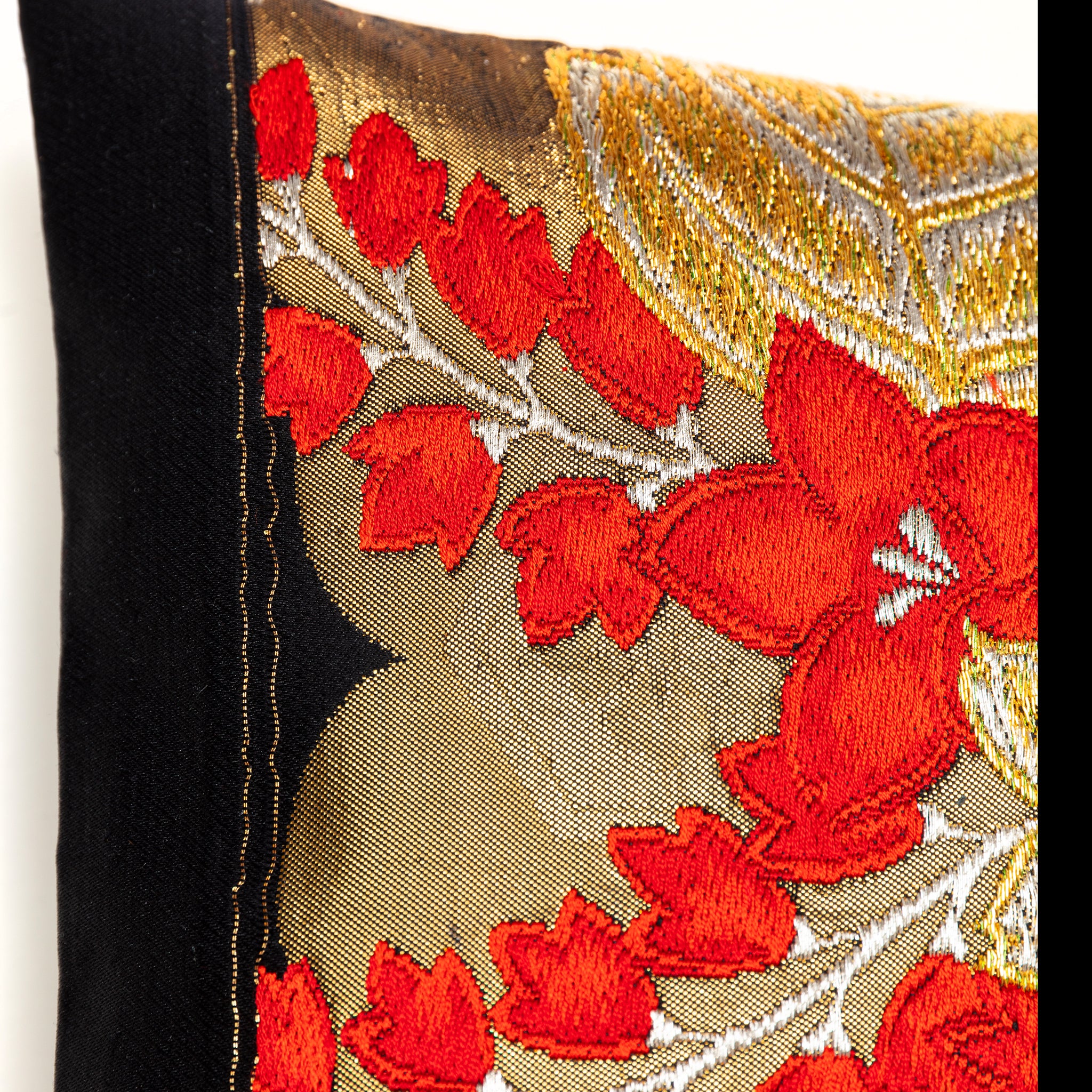 Close-up of the intricate gold embroidery details on the black silk background of the vintage Obi cushion, highlighting