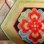 Close-up of gold hexagon accents sewn onto vintage obi silk fabric, highlighting intricate embroidery and textured surface