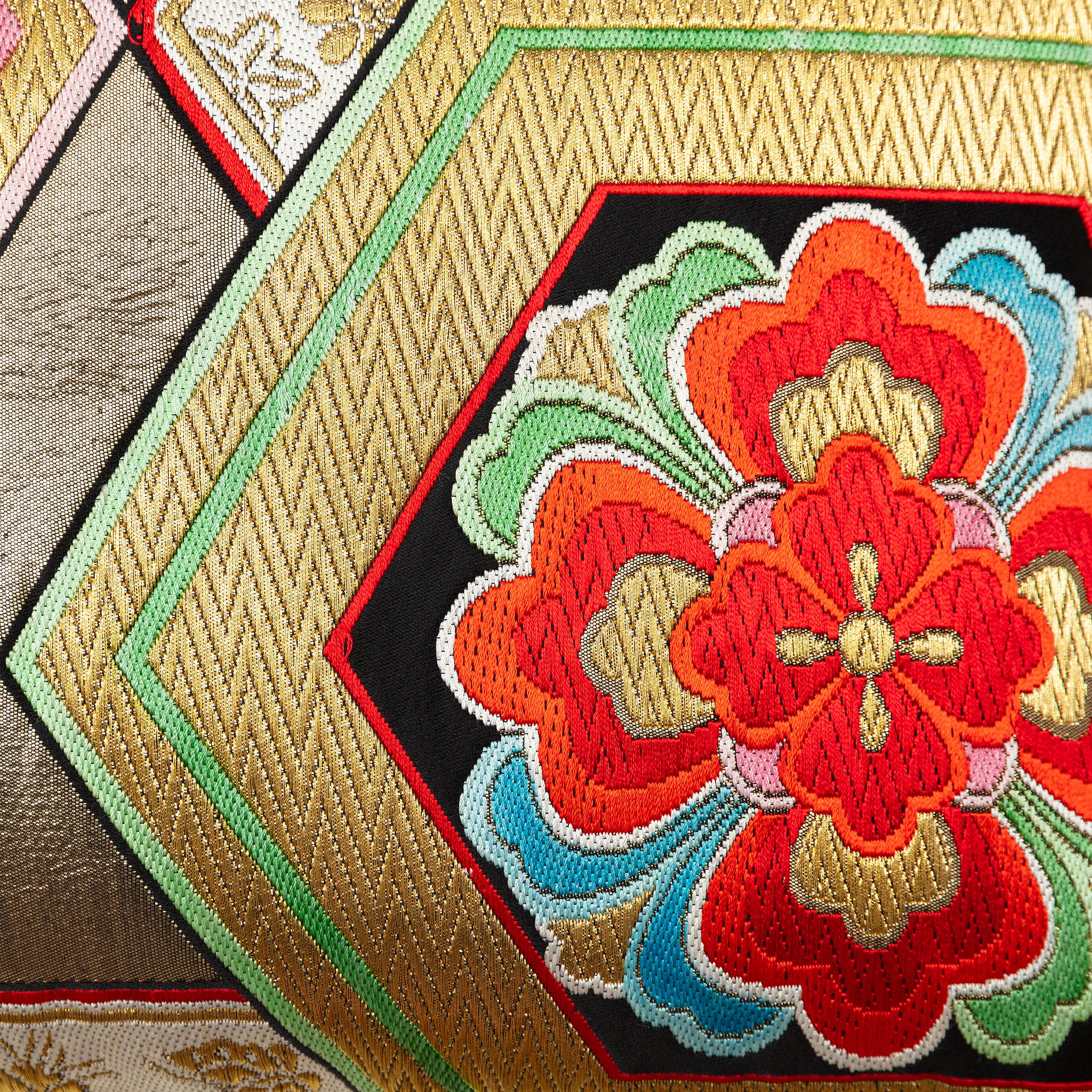 Close-up of gold hexagon accents sewn onto vintage obi silk fabric, highlighting intricate embroidery and textured surface