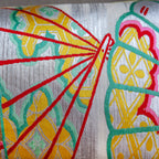 Close-up of yellow velvet bolster pillow edge highlighting vintage kimono silk fan embroidery detail and textured stitching.