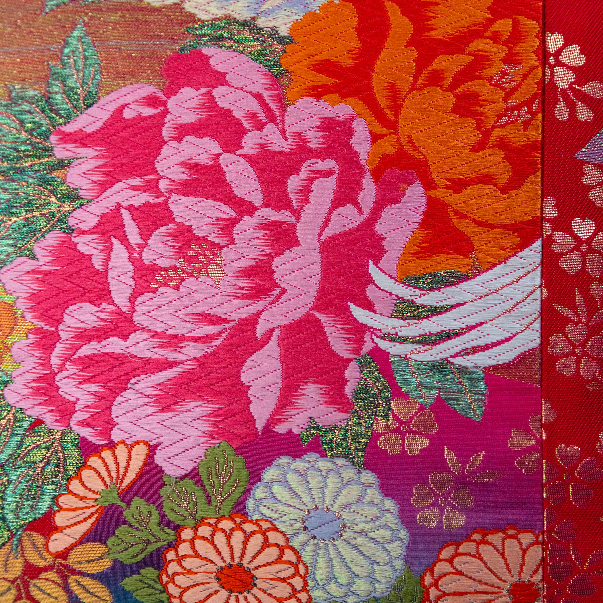 Close-up of pink silk and velvet embroidery detailing the flying cranes motif from a lower angle, highlighting intricate