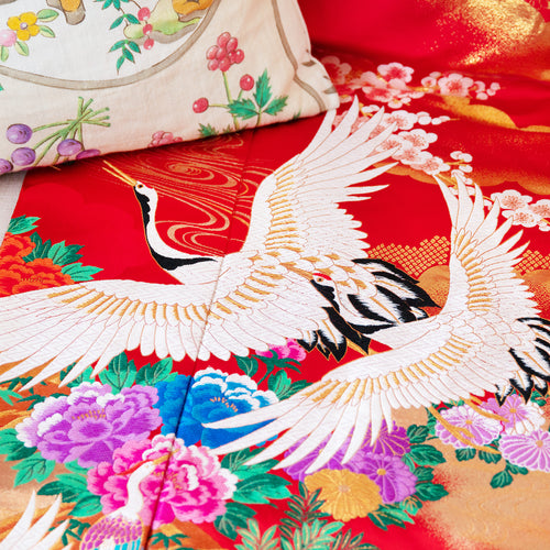 Close-up of the vibrant red silk fabric showcasing intricate vintage floral embroidery details and smooth finish.