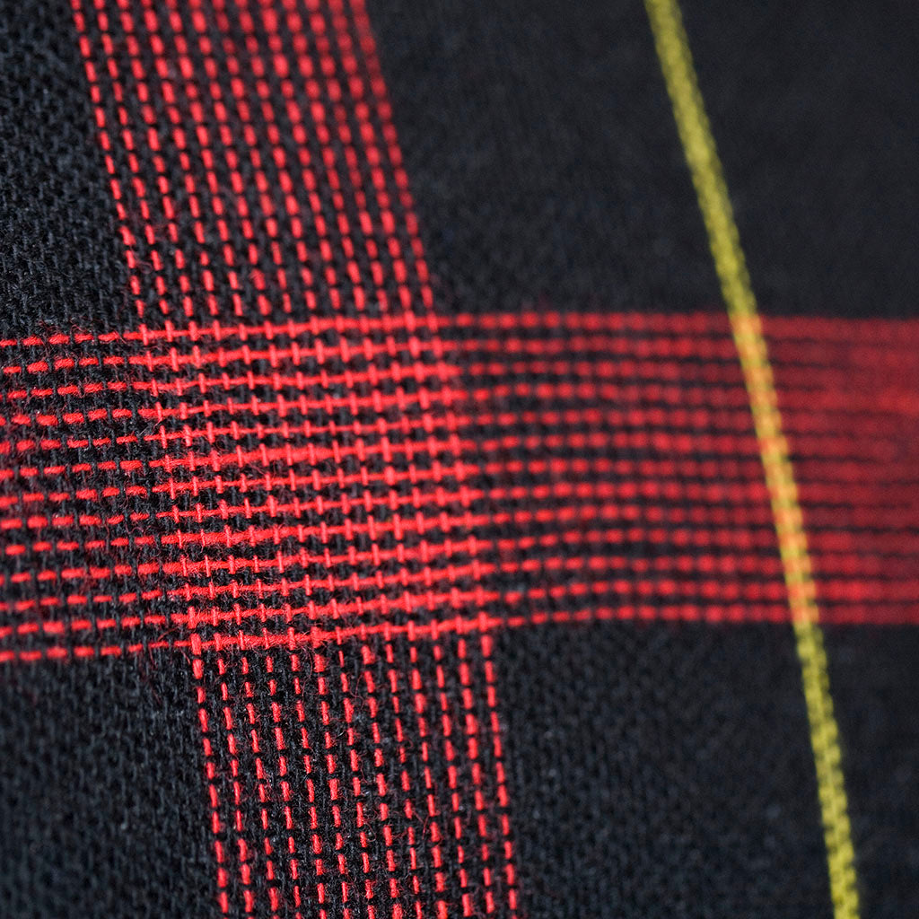 Close-up of navy wool tartan pattern woven texture highlighting intricate thread details and rich color variation.