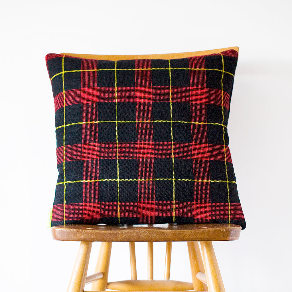 Close-up of navy wool tartan pattern on textured cushion fabric, highlighting intricate weave and subtle color variations