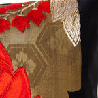 Close-up of vibrant red and gold embroidery details on the vintage black silk Obi cushion's corner, highlighting intricate