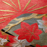 Detail of gold and orange obi pillow showing leaves and pine tree design.