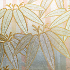 Close-up of the bamboo embroidery detail on the vintage gold pillow's peach velvet back, highlighting intricate stitching