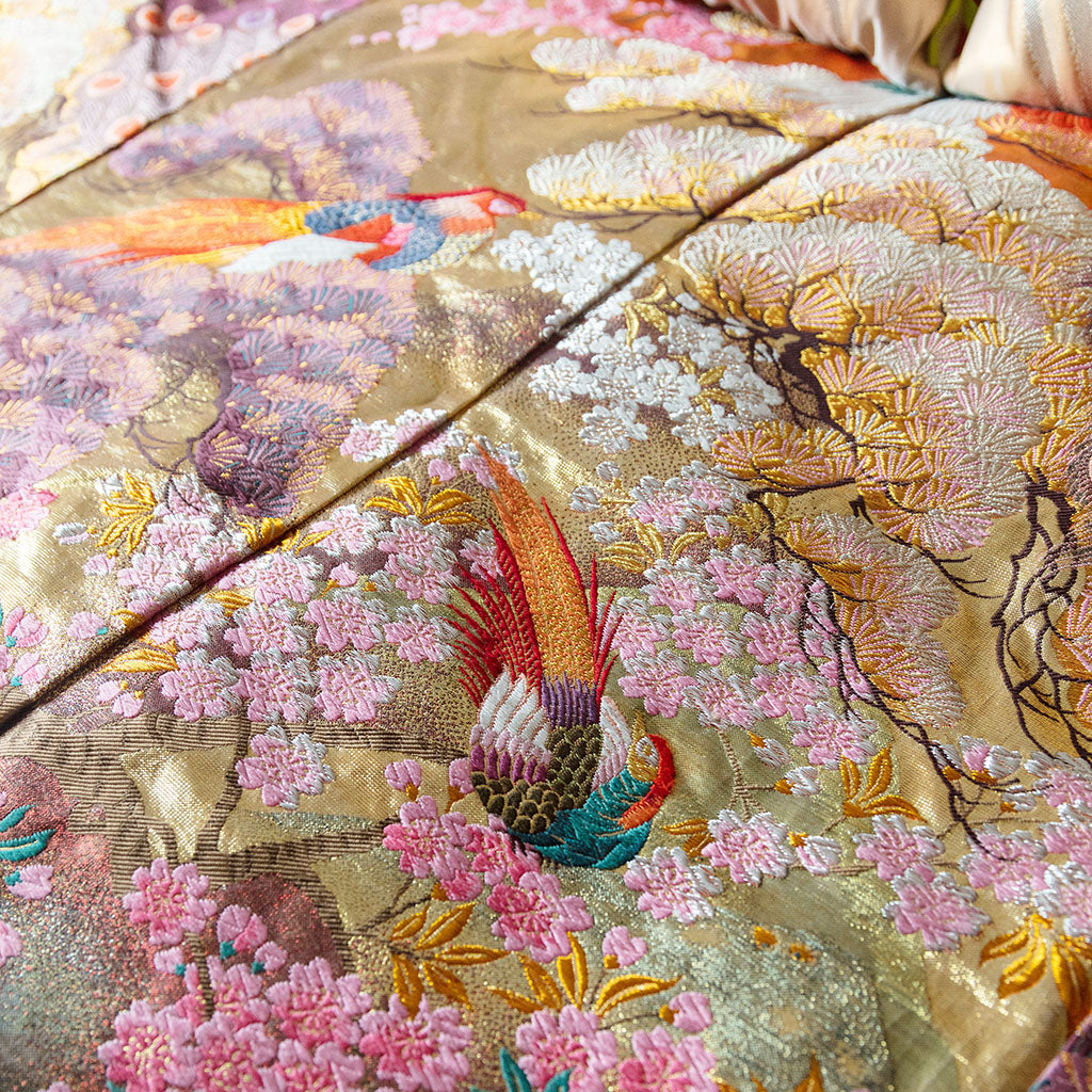 Close-up of vintage kimono-inspired silk throw blanket’s intricate floral embroidery and soft sheen at corner fold.