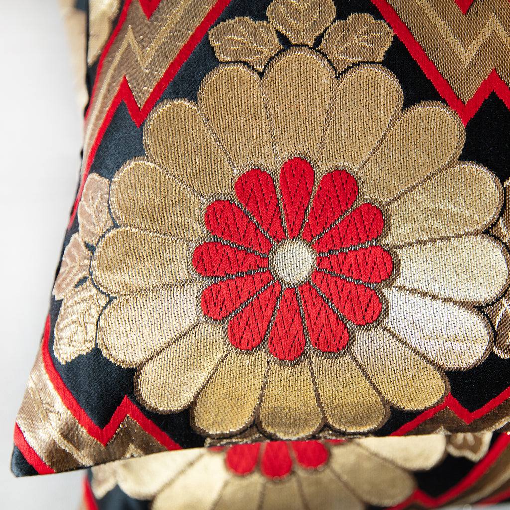 Close-up of intricate gold embroidery and textured silk weave highlighting the ornate floral pattern on the black background