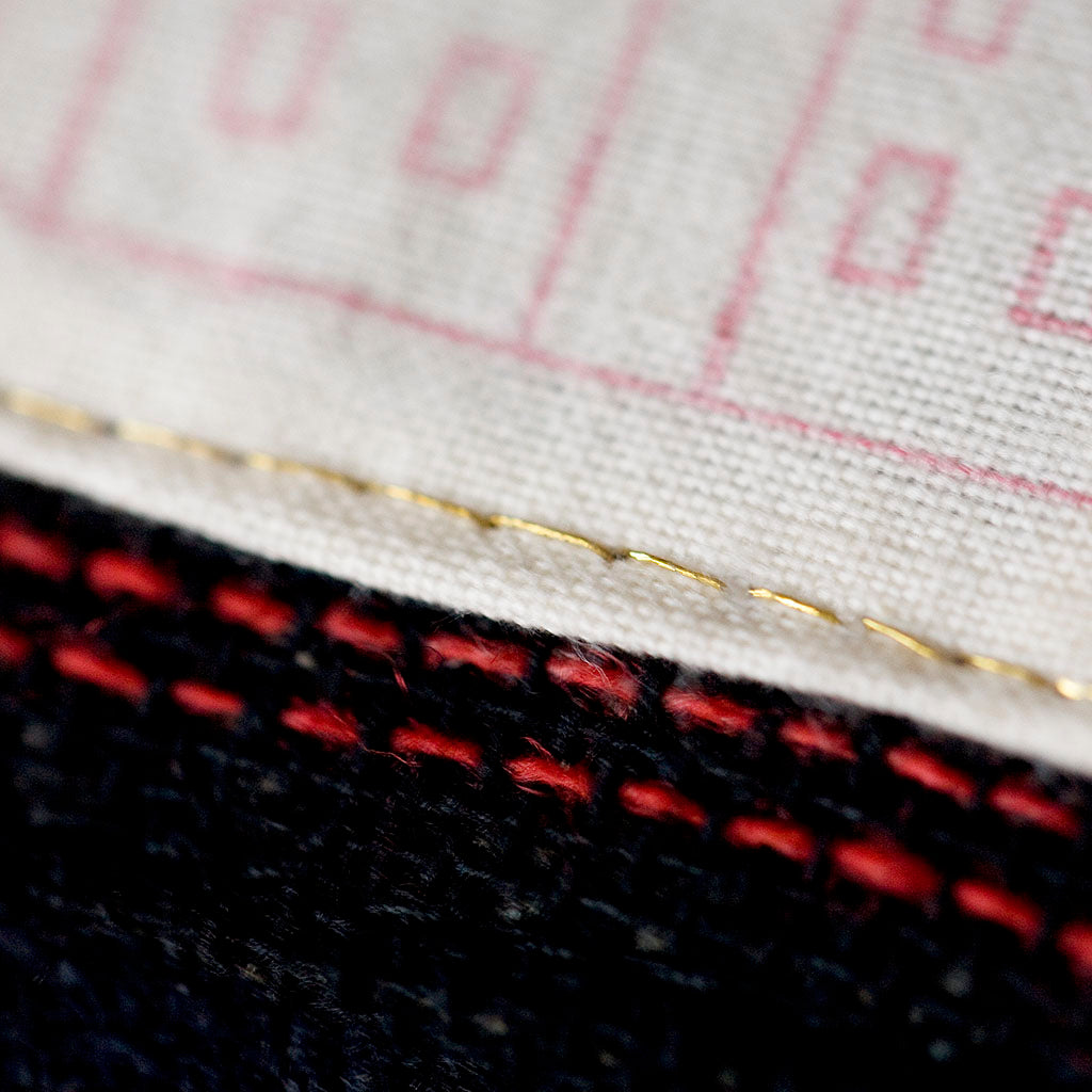 Close-up of navy wool tartan fabric detail highlighting vintage Gannex Ltd Ed branding on the cushion’s corner