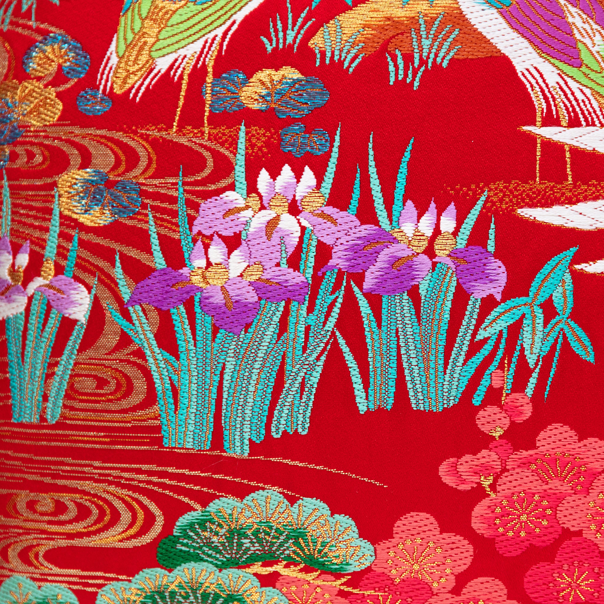 Close-up of the Uchikake square pillow's intricate gold velvet iris embroidery on rich red silk fabric, highlighting