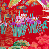 detail of decorative throw pillow showing irises by a stream over woven red silk base