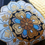 Japanese flower in blue and gold silk, detail of a corner of a black silk obi pillow by Hunted and Stuffed