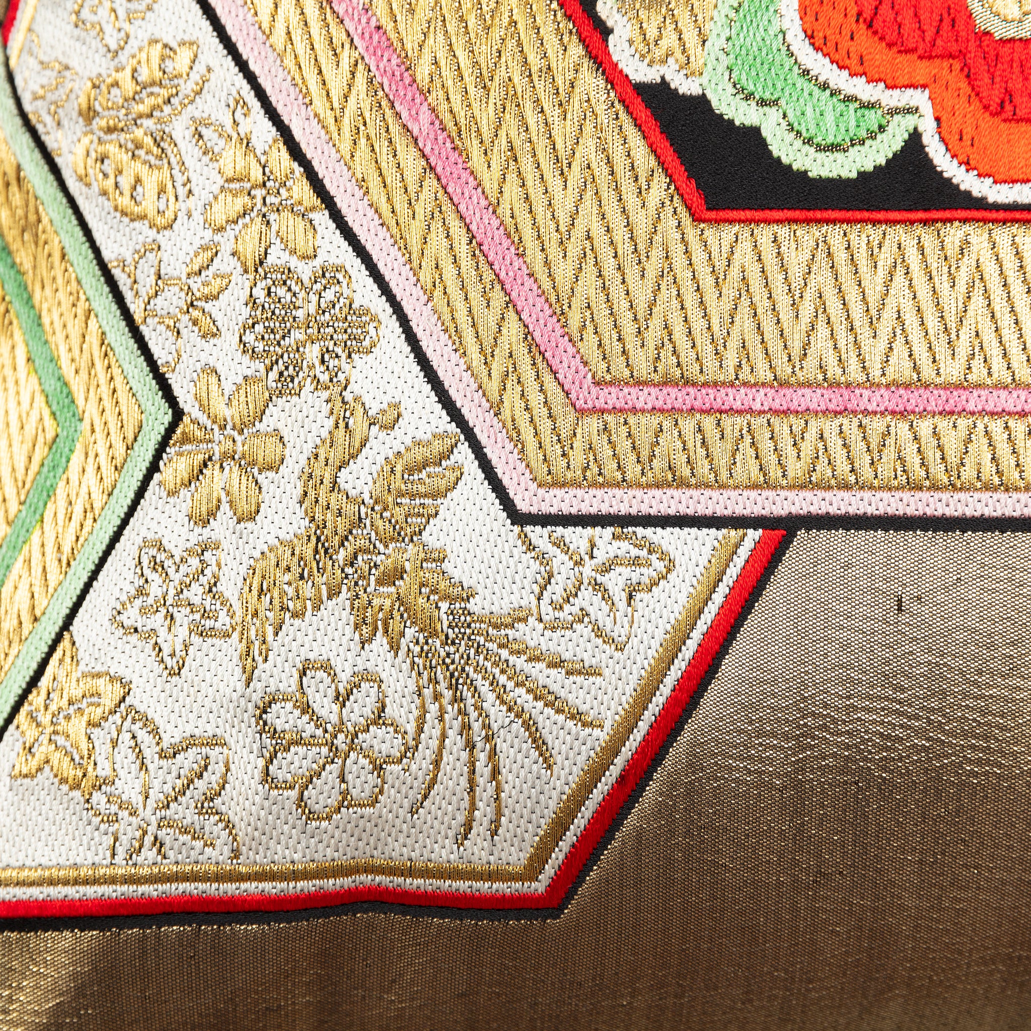 Close-up of gold hexagon accents embroidered onto vintage obi silk with intricate stitching details and subtle sheen.