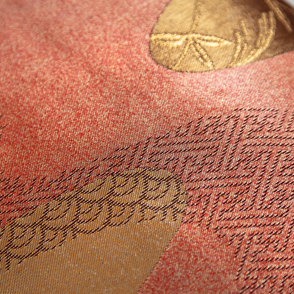 Close-up of the bronze obi cushion’s textured silk fabric and intricate running river embroidery from a slightly angled