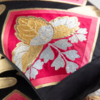 Close-up of black silk fabric with gold thread accents on the Pink Kimono Pillow, highlighting intricate embroidery detail