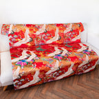 Close-up of vibrant red silk fabric showcasing intricate vintage floral embroidery detail on the throw blanket edge