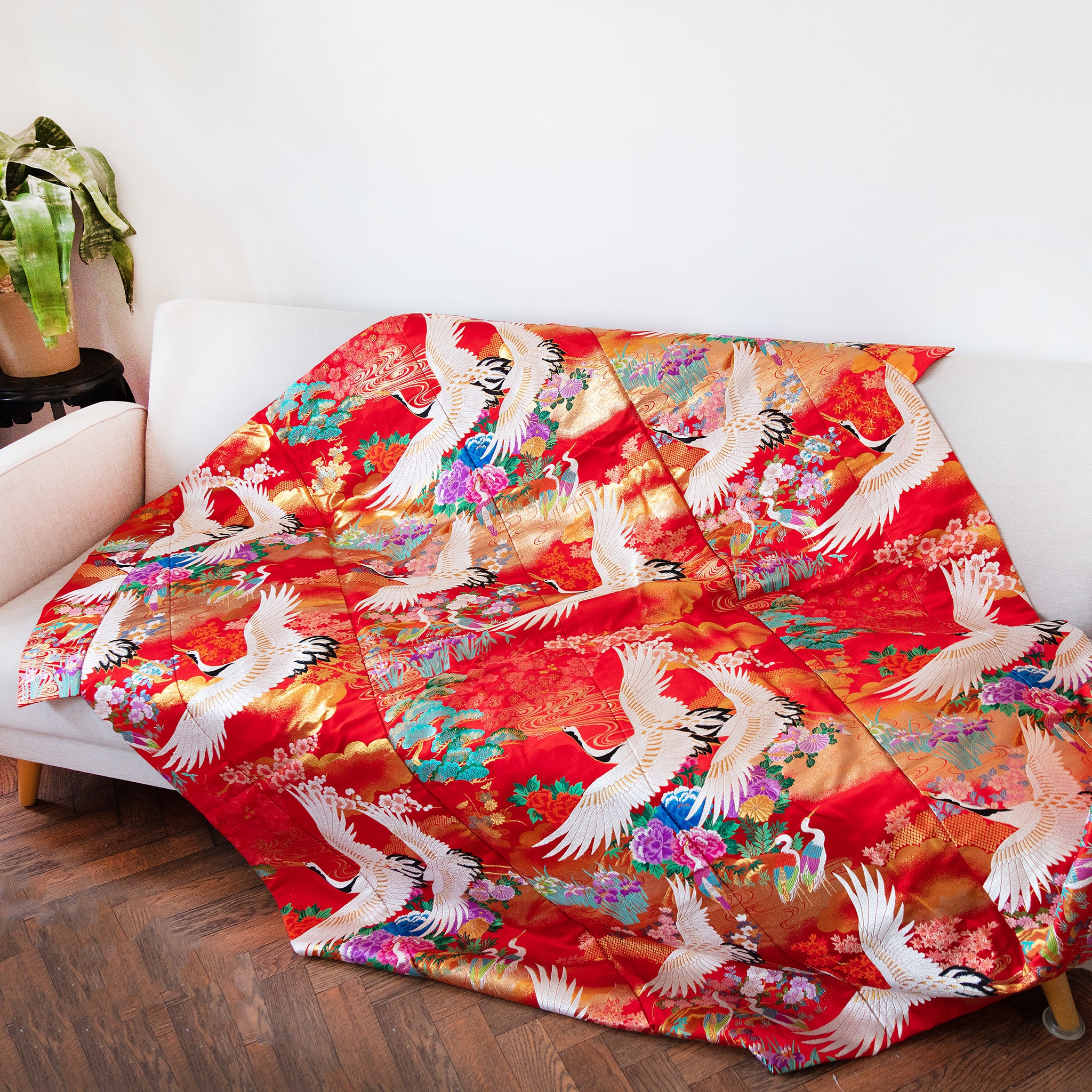 Close-up of textured red silk fabric showing intricate vintage kimono-inspired embroidery detail on the throw blanket