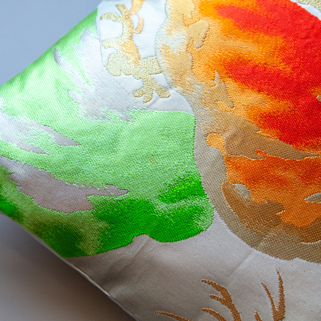 Close-up of vibrant orange and green Matsu Pines embroidery details on the Obi cushion fabric edge